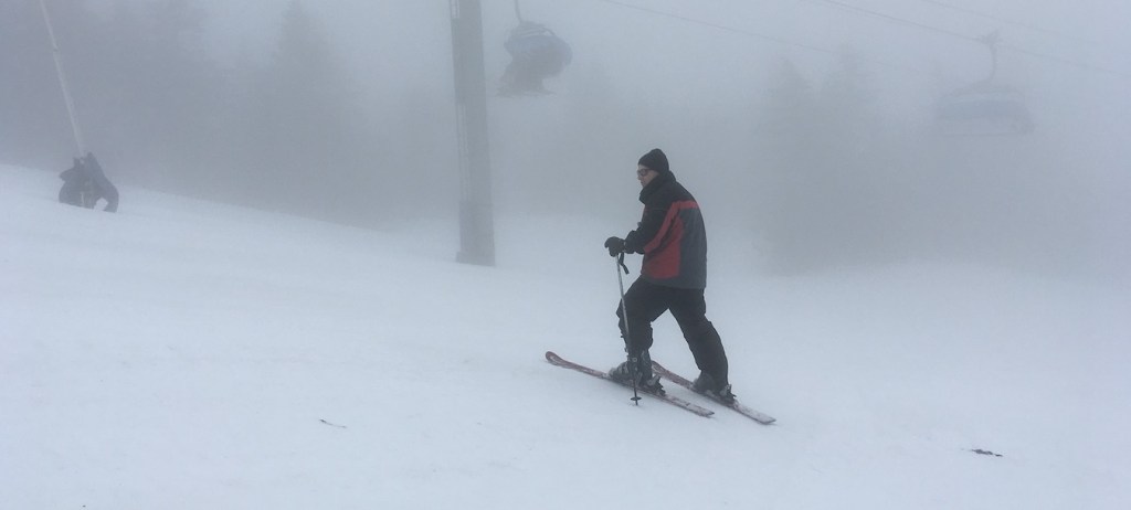 A man skies at Mount Snow on a foggy day