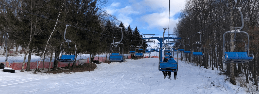 a double chairlift low to the ground on a bluebird day